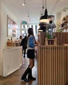 a woman standing in front of a counter at a coffee shop with lots of shelves