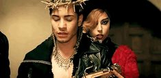 a man and woman dressed in costumes with chains on their heads, one holding a cell phone