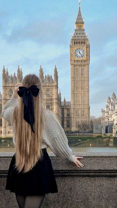 a woman with long blonde hair standing in front of the big ben clock tower