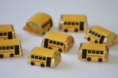 yellow and black school bus candy wrappers on white table with one chocolate bar in the middle