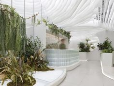 the interior of an office building with plants and greenery on the walls, along with a man walking in the background