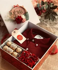 an open box with some wine and chocolates in it on a table next to flowers