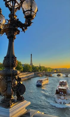 the boats are traveling down the river in front of the light pole and lampposts