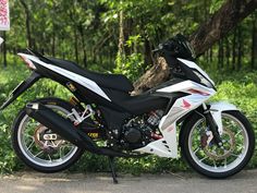 a white and black motorcycle parked next to a tree