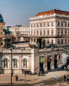 an old building in the middle of a city square with many people walking around it