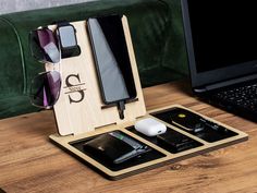 an open laptop computer sitting on top of a wooden table next to sunglasses and cell phone