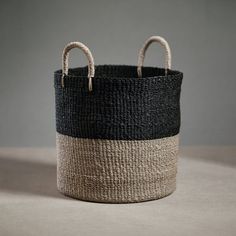 a black and white basket sitting on top of a table next to a gray wall