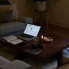 an open laptop computer sitting on top of a wooden table in front of a couch