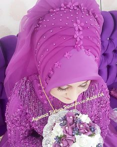 a woman wearing a purple turban and holding a white flower in her hand