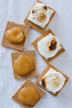 small crackers with peanut butter and jelly on them sitting on a white tablecloth