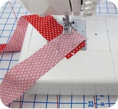 the sewing machine is working on the red and white ribbon that has been sewn