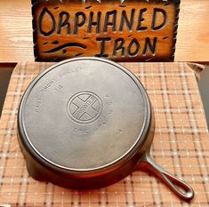 a cast iron skillet sitting on top of a table next to a wooden sign