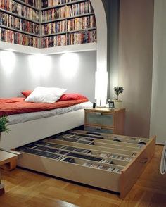 there is a bed with lots of books on the bottom and bottom shelves above it