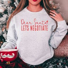 a woman wearing a sweatshirt with the words dear santa, lets negotiate on it