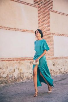 a woman in a blue dress is walking down the street with her hand on her hip