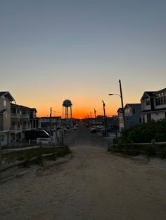 the sun is setting behind some houses and water towers