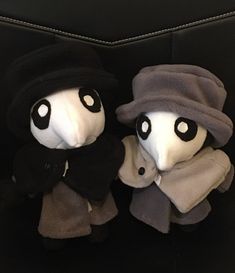 two stuffed animals wearing hats and scarves are sitting on a black leather chair together