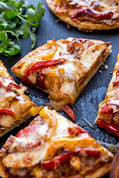 several slices of pizza sitting on top of a black tray next to green leafy garnish