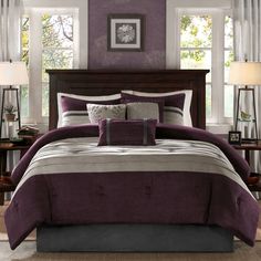 a bed with purple and grey comforters in a bedroom