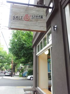 a sign hanging from the side of a building that says salt and straw on it