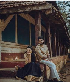 a man and woman sitting next to each other in front of a wooden structure with windows