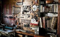 a room filled with lots of tools and assorted items hanging on the wall next to a desk