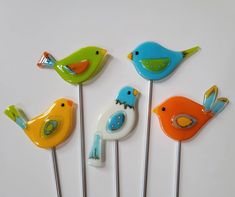 five colorful birds on top of each other on toothpicks in the shape of pins