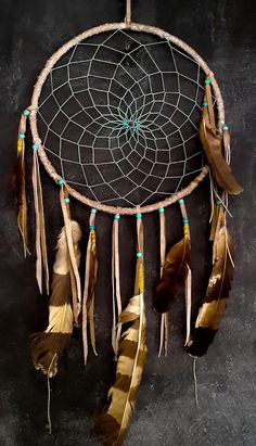 a dream catcher with feathers hanging from it's side