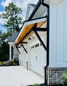 a white garage with black trim and wood roof