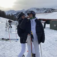 two people standing in the snow on skis