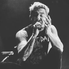 black and white photograph of a man with his hands on his face as he sings into a microphone