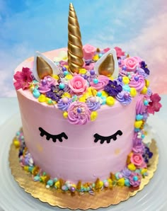 a pink cake decorated with flowers and unicorn ears