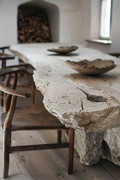 an old table with two bowls on it and some chairs in front of the table