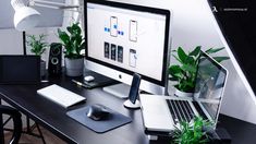 a desk with a laptop, monitor and keyboard on it next to a potted plant