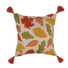 an orange and green leaf pillow with red tassels on the front, sitting on a white background