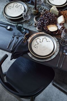 the table is set with black and white plates, silverware, and wine glasses