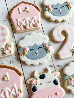 decorated sugar cookies with farm animals and flowers on white wooden table top, for baby shower or first birthday party