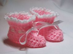 a pair of pink crocheted baby booties with white trim