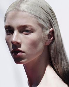 a woman with long blonde hair and no shirt is posing for the camera while wearing an earring