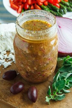 a jar filled with food sitting on top of a wooden cutting board next to vegetables