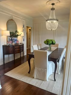 a dining room table with white chairs and a chandelier