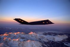 an airplane flying over some snow covered mountains in the evening sky with its lights on