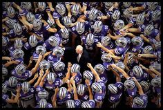 a large group of football players standing in the middle of a circle with their hands up