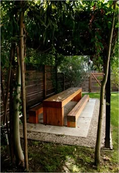 a wooden bench sitting in the middle of a lush green park next to tall trees