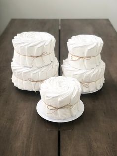 four rolls of toilet paper on a table with twine tied around the edges and sitting on top of each other