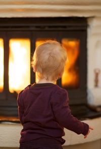 a toddler standing in front of an oven with the door open and flames coming out