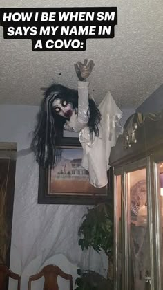 a creepy doll hanging from the ceiling in a room with a framed photograph above it that says, how i be when sm says my name in a covo