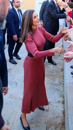 a woman in a red dress is reaching out her hand to shake someone's hand