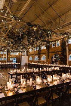 the tables are set up with candles and greenery hanging from the ceiling above them