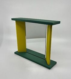 a green and yellow shelf with a mirror on it's side, against a white background